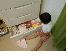 子どもが箪笥の引き出しを開けて整理している